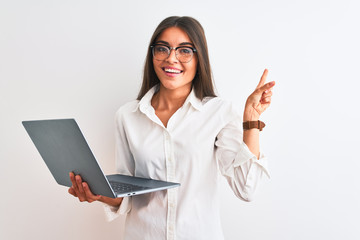 Poster - Beautiful businesswoman wearing glasses using laptop over isolated white background very happy pointing with hand and finger to the side