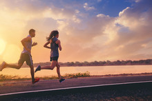 Young Couples Running Sprinting On Road. Fit Runner Fitness Runner During Outdoor Workout With Sunset Background