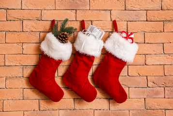 Christmas socks with gifts hanging on brick wall