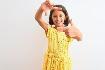 Sticker - Young beautiful child girl wearing yellow floral dress standing over isolated white background smiling making frame with hands and fingers with happy face. Creativity and photography concept.