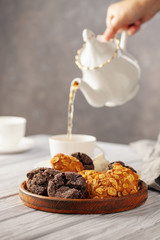 Set of different cookies in a plate and tea on a wooden background.