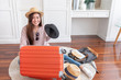 © weedezign - Young asian woman traveler prepare cloth and stuff into orange suitcase for holiday vacation at home.backpacker travel concept