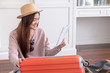 © weedezign - Young asian woman traveler prepare cloth and stuff into orange suitcase for holiday vacation at home.backpacker travel concept