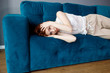 © Dmitrii Kotin - Young woman lying on couch and suffering from headache at home.