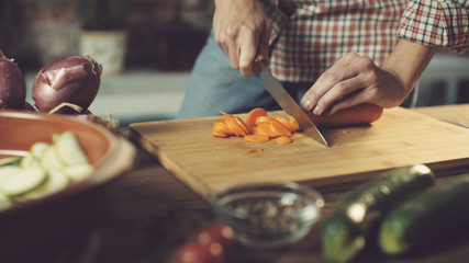 Wall Mural - Woman slicing fresh vegetables and preparing a healthy meal