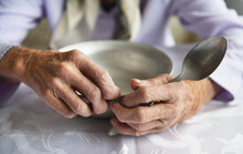 View From Above.The Hands Of An Old Grandmother Of 90 Years Are Holding An Empty Aluminum Bowl And Spoon, Poverty And Poverty, The Hunger Of The Older Generation.