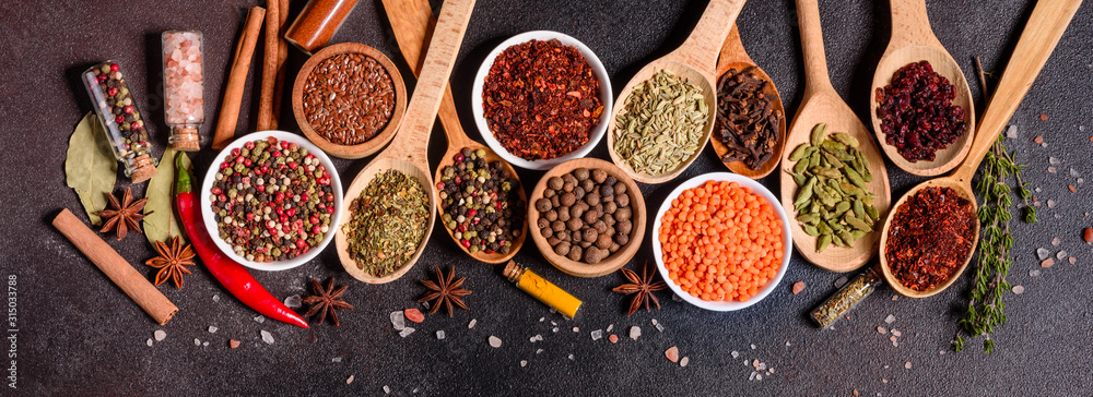 A set of spices and herbs. Indian cuisine. Pepper, salt, paprika, basil and other on a dark background - obrazy, fototapety, plakaty 