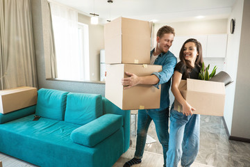 Wall Mural - young couple man and woman looking happy standing with boxes in their hands in new appartment unpacking boxes