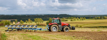 Farmer In Red Tractor Preparing Land With Plow For Sowing
