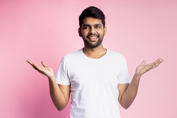 Portrait of handsome Indian guy standing on pink background