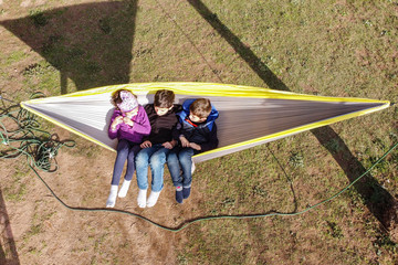 Three kids relaxing on a hammock. Air view