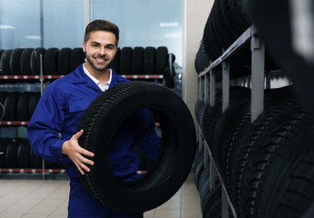 Wall Mural - Male mechanic with car tire in auto store