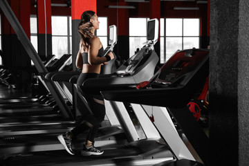 Wall Mural - Young woman working out on treadmill in modern gym