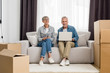 © LIGHTFIELD STUDIOS - mature man with laptop and woman smiling at camera in new house