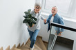 © LIGHTFIELD STUDIOS - mature woman with plant holding hands with man in new house