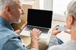 © LIGHTFIELD STUDIOS - cropped view of mature man with laptop and woman holding empty card in new house