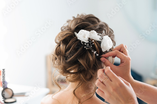 Cuadros en Lienzo hairdresser makes an elegant hairstyle styling bride with white flowers in her h