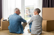 © LIGHTFIELD STUDIOS - back view of mature man and woman sitting on floor in new house