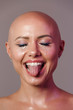 Portrait of caucasian half-naked bald woman sticking her tongue out