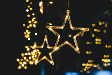 Wall Mural - Bright luminous stars of garland on a dark background and beautiful bokeh. New Year's festive interior decoration