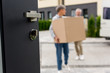 © LIGHTFIELD STUDIOS - selective focus of door and mature man and woman bringing boxes to new house on background