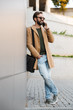 © Drobot Dean - Image of man talking on smartphone and standing by building outdoors