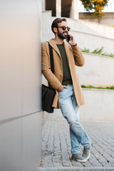 Poster - Image of man talking on smartphone and standing by building outdoors