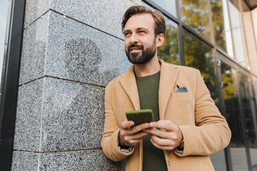 Poster - Image of bearded man holding smartphone while walking on street