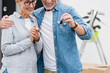 © LIGHTFIELD STUDIOS - cropped view of mature man holding keys of new house and smiling woman looking at it