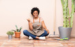 © luismolinero - Gardener woman sitting on the floor pointing to the side to present a product