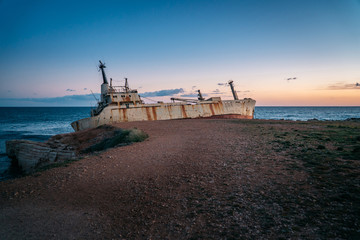 Sticker - An old ship stranded stands on the seashore.