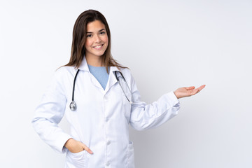 Teenager girl over isolated white background wearing a doctor gown and presenting something