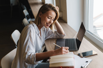 Sticker - Photo of smiling blonde woman making notes while working