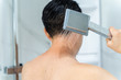 © twinsterphoto - Back view of black haired undressed man pouring hot water from shower head in modern bathroom