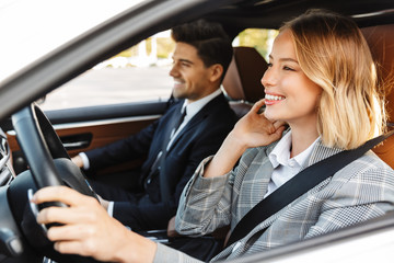 image of young caucasian businesslike man and woman riding in car