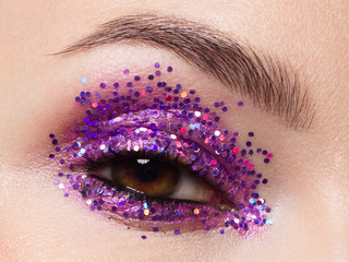 Wall Mural - Close eye with colorful eyeshadow. Macro shot of opened human female eye. Woman with evening beauty makeup. Girl with perfect skin and eyebrow. Women cosmetics, extremely long eyelash and pink glitter