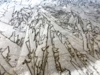 Patterns on frozen ice of lake close-up. White ice background. Natural background