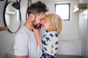 mature father with small son indoors in bathroom, having fun.