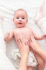 baby massage. female therapist gently massaging newborn baby boy. mother applying body lotion to her