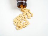 Fototapeta Desenie - Yellow tablets vitamin C medicine from bottle on white background. Vitamin C 500 milligram pills.
