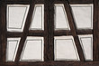 Detail eines alten Fachwerks aus dunkelbraunen Holzbalken und weiß verputzten Zwischenräumen mit aufgemaltem Dekor