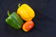 Yellow and green bell peppers with red tomatoes On a black background