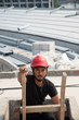 © Arthiti - Black bearded engineer wear red hard hat and black working suit climbing wood ladder in construction site