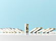 © Andy Roberts/Caia Image - Dominos falling around standing domino against blue background