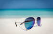 © Tom Merton/Caia Image - Close up aviator sunglasses in sand on sunny tropical ocean beach