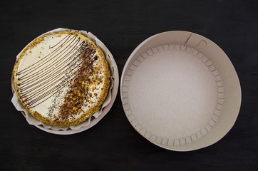 tasty cake and box on a black, wooden table. View from above.