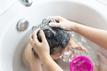 Mom's hands are washed the little kids head in the bathroom