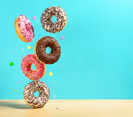 Flying donuts. Mix of multicolored sweet doughnuts with sprinkel on turqouise blue background falling on the table.