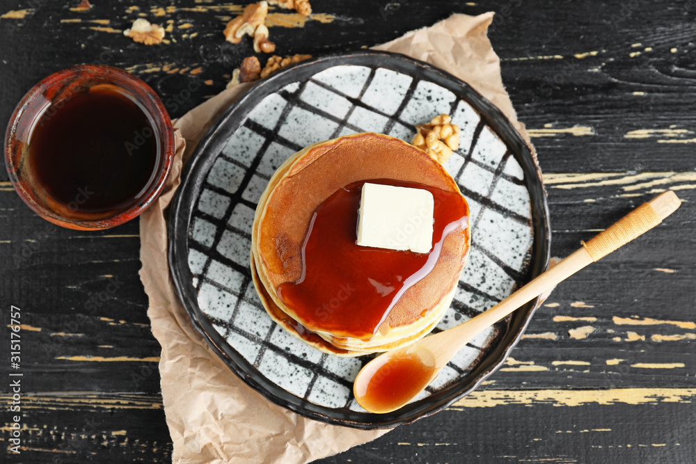 Plate with stack of tasty pancakes on table