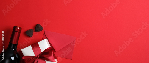 Fotomural Valentine's day banner mockup with wine bottle, red envelope, valentine gift, heart shaped candies on red background with copy space